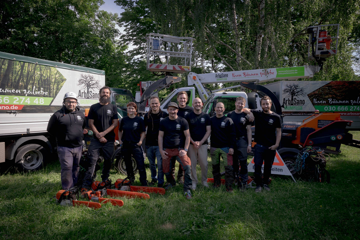 Das Team von ArboSano vor dem eigenen Fuhrpark mit Hebebühne und Großhäckslern im Großraum Berlin.
